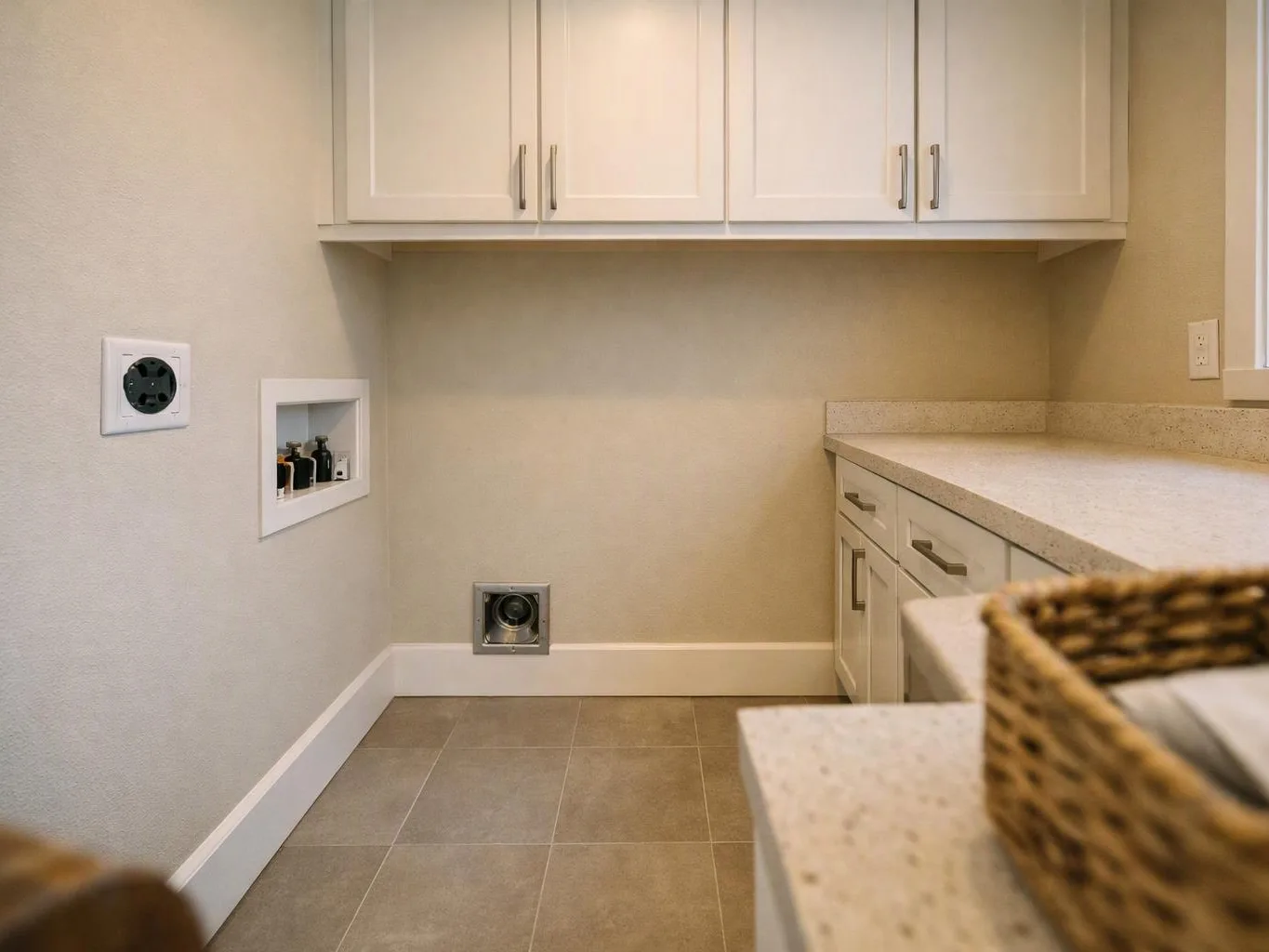 A bright laundry room shows white cabinets, a countertop, tiled floor, and hookups for a washer and dryer