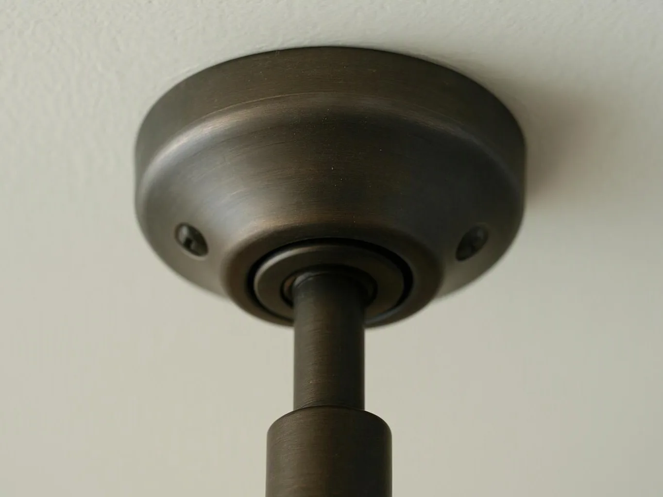 Close-up of a dark bronze ceiling light fixture mounted against a pale wall